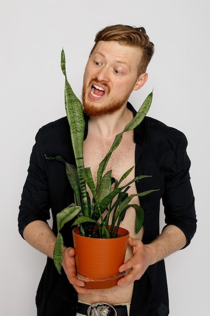 Un jeune homme souriant tient une plante dans ses mains