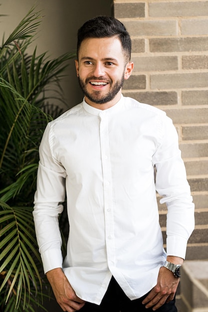 Jeune homme souriant, vêtu d'une chemise blanche au bureau