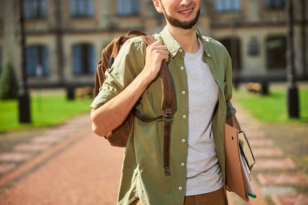 un jeune homme avec un sourire heureux portant un sac à dos sur son épaule