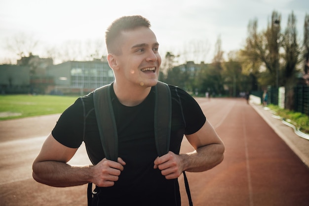 Un jeune homme sourit alors qu'il se tient sur la piste sportive