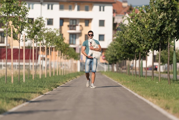 Un jeune homme et un Spitz allemand se promènent dans le parc, il tient le chien en laisse