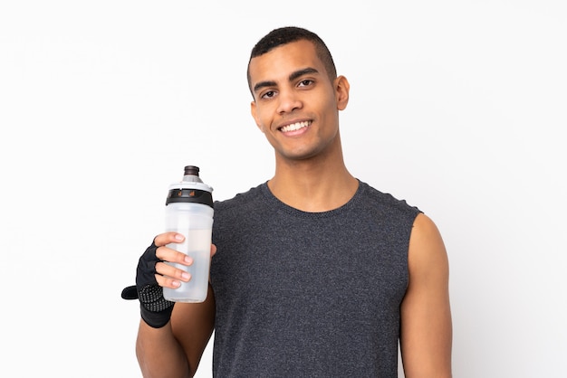 Jeune homme de sport afro-américain sur mur blanc isolé avec bouteille d'eau de sport