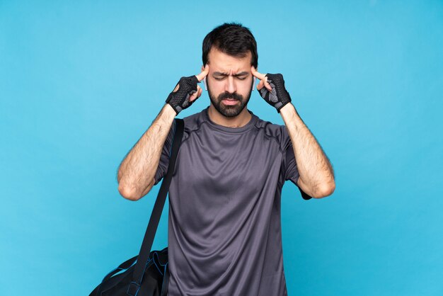 Jeune homme sport avec barbe sur bleu isolé avec maux de tête