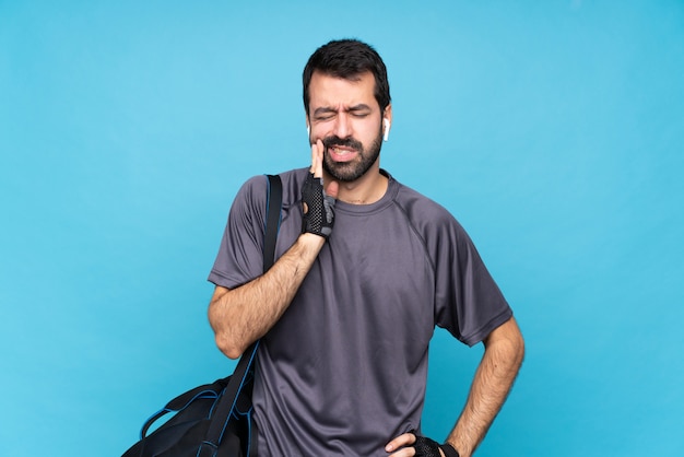 Jeune homme sport avec barbe sur fond bleu isolé avec maux de dents