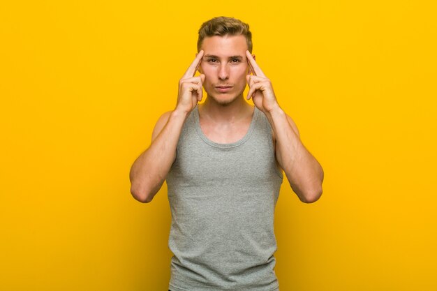 Jeune homme de sport caucasien concentré sur une tâche, gardant l'index pointant la tête.