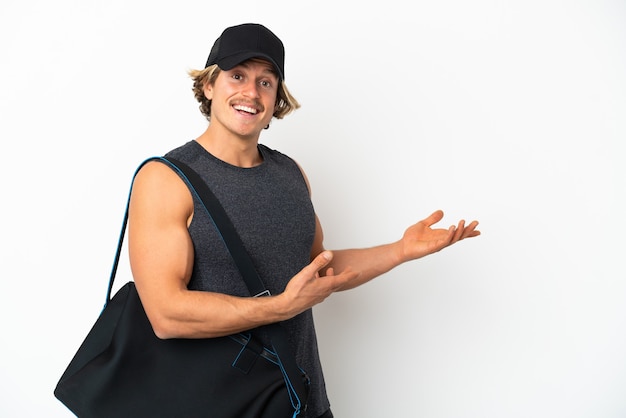 Jeune homme de sport avec sac de sport isolé sur un mur blanc étendant les mains sur le côté pour inviter à venir