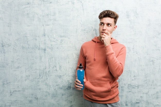 Jeune Homme Sportif Détenant Une Boisson énergisante Détendue Pensant à Quelque Chose En Regardant Un Espace De Copie.