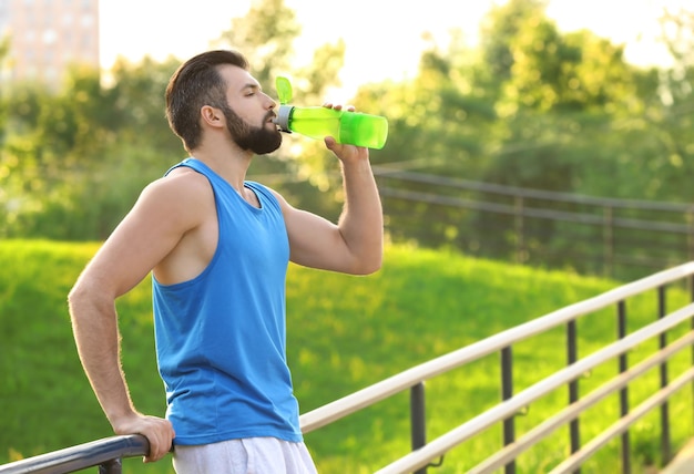 Jeune homme sportif de l'eau potable dans le parc