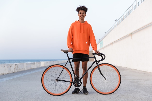 Jeune homme sportif à l'extérieur sur la plage à vélo