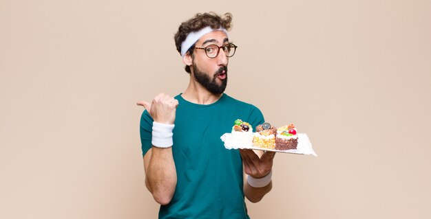 Jeune homme sportif avec des gâteaux contre un mur plat