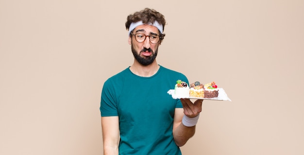 Jeune homme sportif avec des gâteaux sur un mur plat