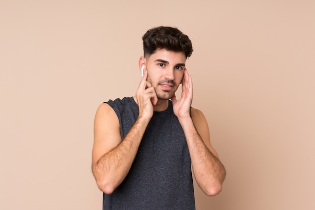 Jeune homme sportif sur musique écoute mur isolé