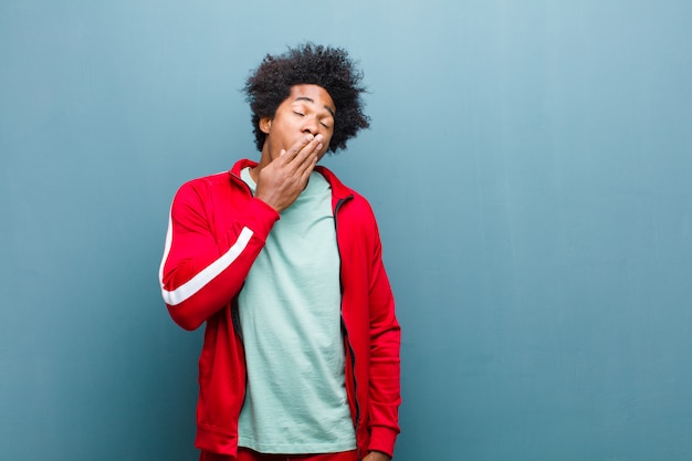 Jeune Homme Sportif Noir Bâillant Paresseusement Tôt Le Matin, Se Réveillant Et Ayant L'air Endormi, Fatigué Et Ennuyé Contre Le Mur De Grunge