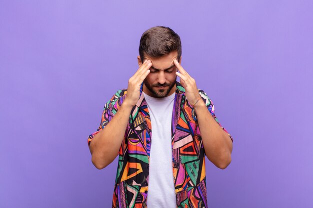 Jeune homme à la stress et frustré, travaillant sous pression avec un mal de tête et troublé par des problèmes