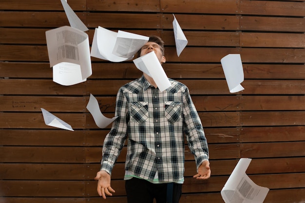 Un jeune homme stressé jette des fichiers papier froissés dans les concepts de liberté de l'air