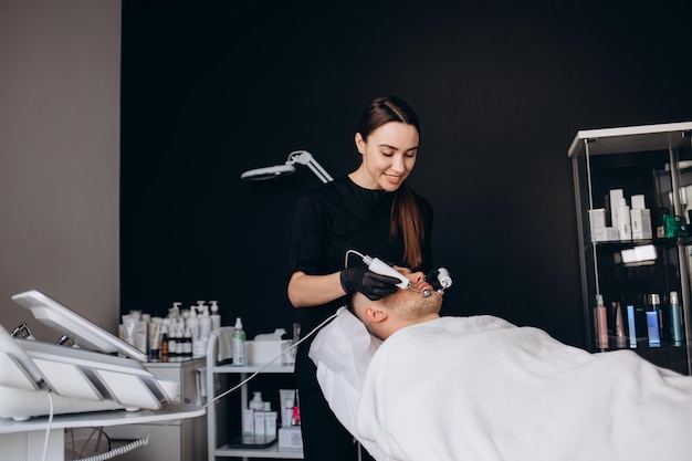 Jeune homme subissant une thérapie par micro-courant dans un salon de beauté