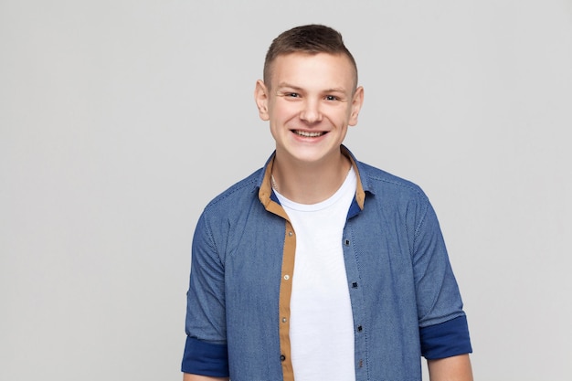 Jeune homme de succès portant une chemise bleue regardant la caméra et un sourire à pleines dents