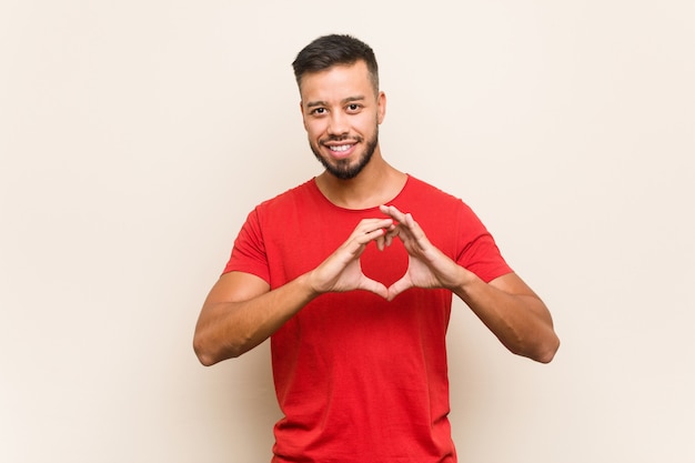 Jeune homme sud-asiatique souriant et montrant une forme de coeur avec les mains.