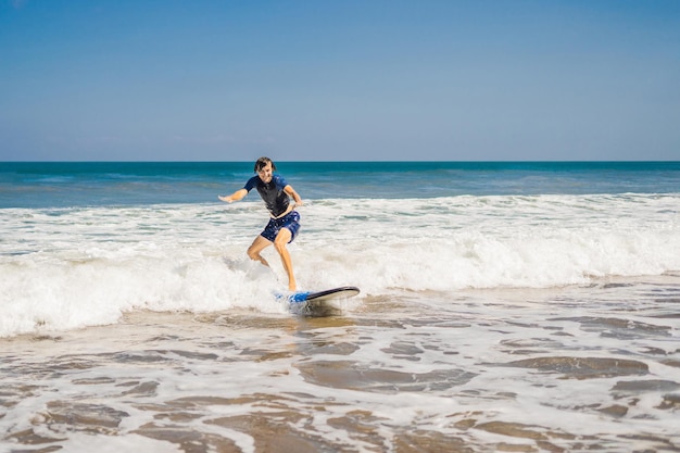 Jeune homme, surfeur débutant apprend à surfer sur une écume de mer sur l'île de Bali