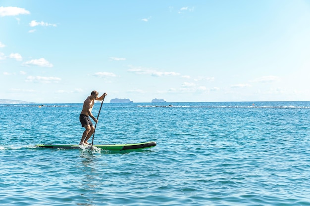 Jeune homme surfeur équitation stand up paddleboard dans l'océan