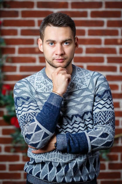 Jeune homme en sweat-shirt contre un mur de briques