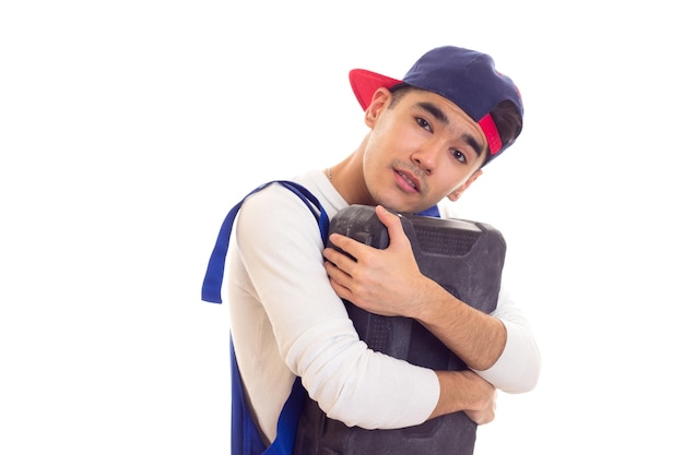 Jeune homme sympa en chemise blanche et combinaison bleue avec des gants orange et une boîte à outils bleue