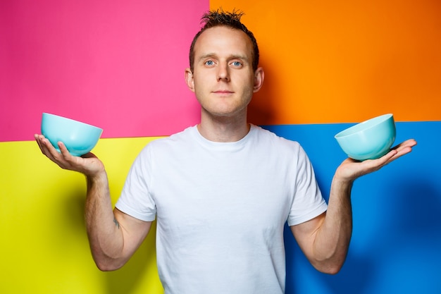 Jeune homme en T-shirt blanc, fond coloré, ustensiles de cuisine, cuisinier, photo d'émotions