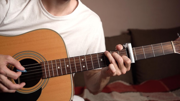 Jeune homme en t-shirt blanc jouant de la guitare acoustique