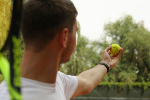 Jeune homme en t-shirt blanc servir la balle de tennis