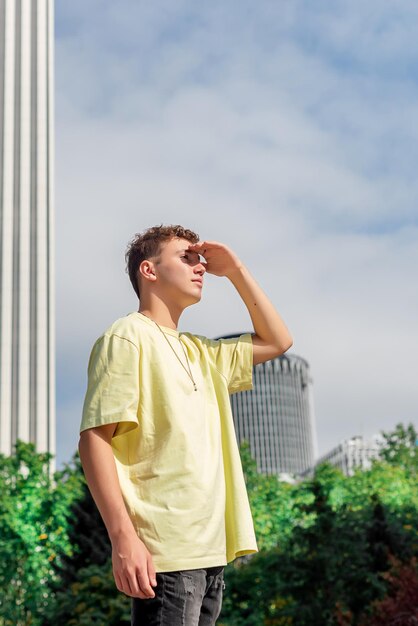 Jeune homme en T-shirt jaune regardant l'horizon avec sa main sur son front