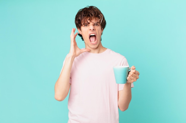 Jeune homme avec une tasse de café criant avec les mains en l'air