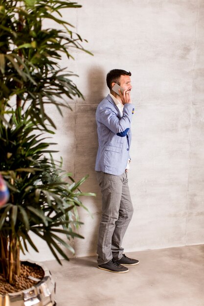 Photo jeune homme avec un téléphone portable au mur