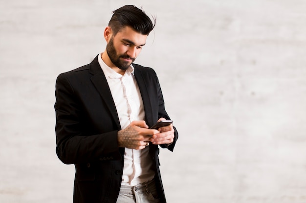 Jeune homme avec un téléphone portable au mur