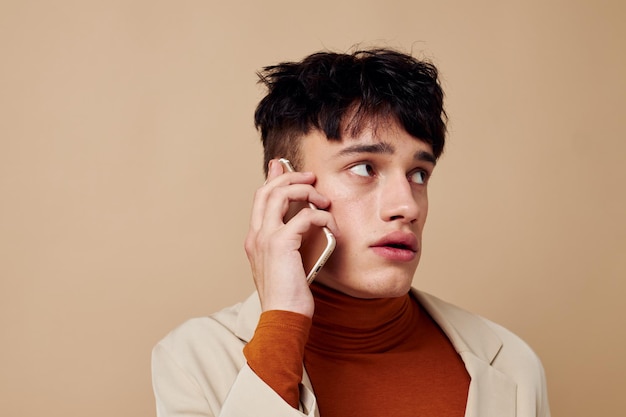 Un jeune homme téléphone portable dans les mains de la communication dans un fond clair de mode costume inchangé