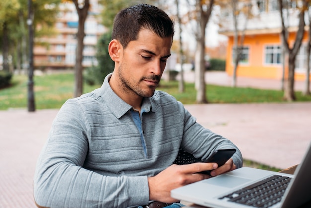 Jeune homme avec téléphone portable et ordinateur