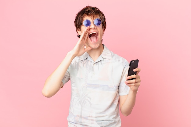 Jeune Homme Avec Un Téléphone Portable Se Sentant Heureux, Donnant Un Grand Cri Avec Les Mains à Côté De La Bouche