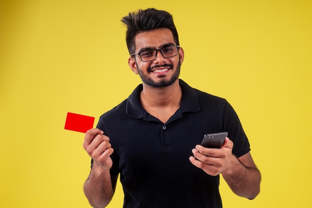 Jeune homme tenant une carte de visite en studio fond jaune.