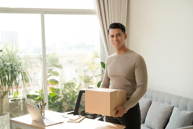 Jeune homme tenant des cartons à l'intérieur