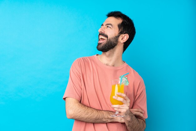 Jeune homme tenant un cocktail heureux et souriant