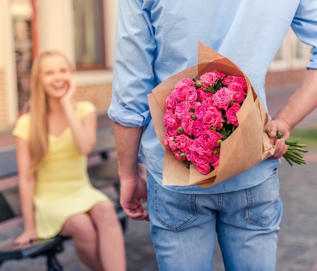 jeune homme tenant des fleurs derrière son dos