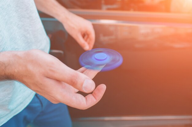 Jeune homme tenant et jouant avec fidget spinner.