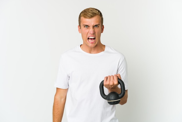Jeune homme tenant un kettlebell criant très en colère et agressif