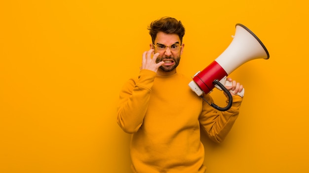 Jeune homme tenant un mégaphone en colère et contrarié