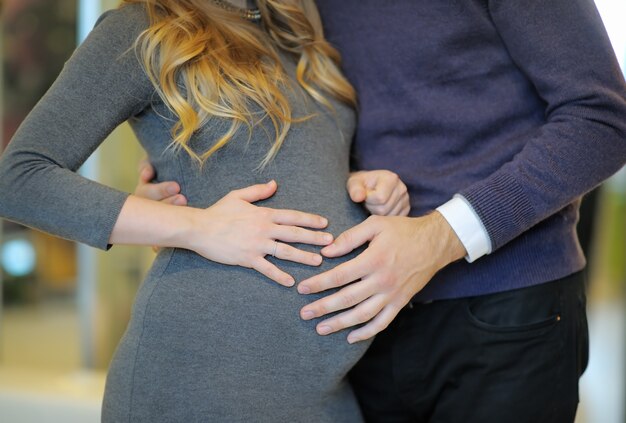 Jeune homme tenant par la main sur le ventre de femme enceinte