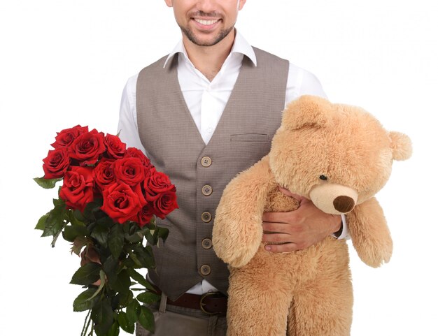 Jeune homme tenant une peluche et des roses.