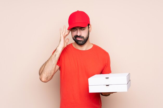 Jeune homme tenant une pizza avec mal de tête