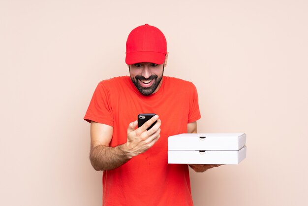 Jeune homme tenant une pizza sur surprise isolée et envoyant un message