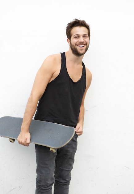 Jeune homme tenant la planche à roulettes sur fond blanc