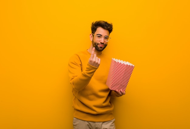 Jeune homme tenant des popcorns invitant à venir