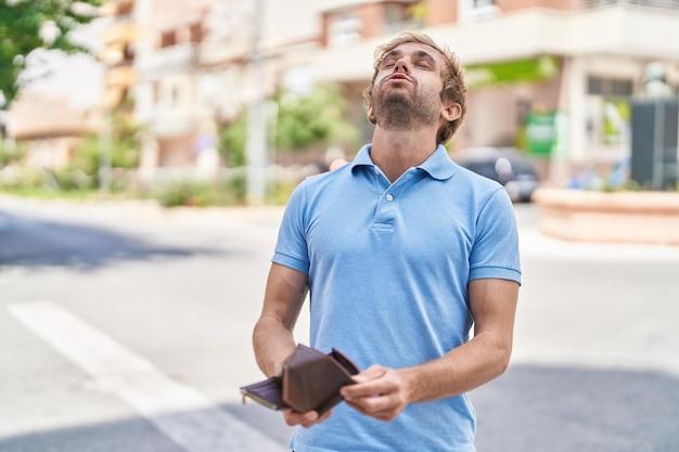 Jeune homme tenant un portefeuille vide dans la rue